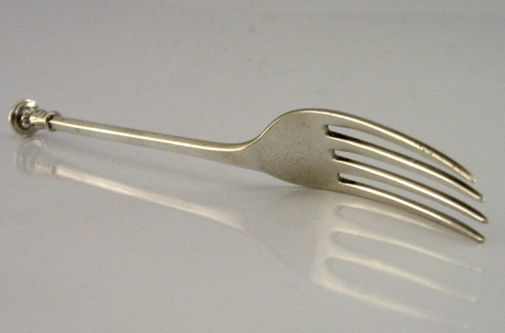 A Victorian sterling silver seal top fork featuring four tines and hallmarks along the slender stem. View IV