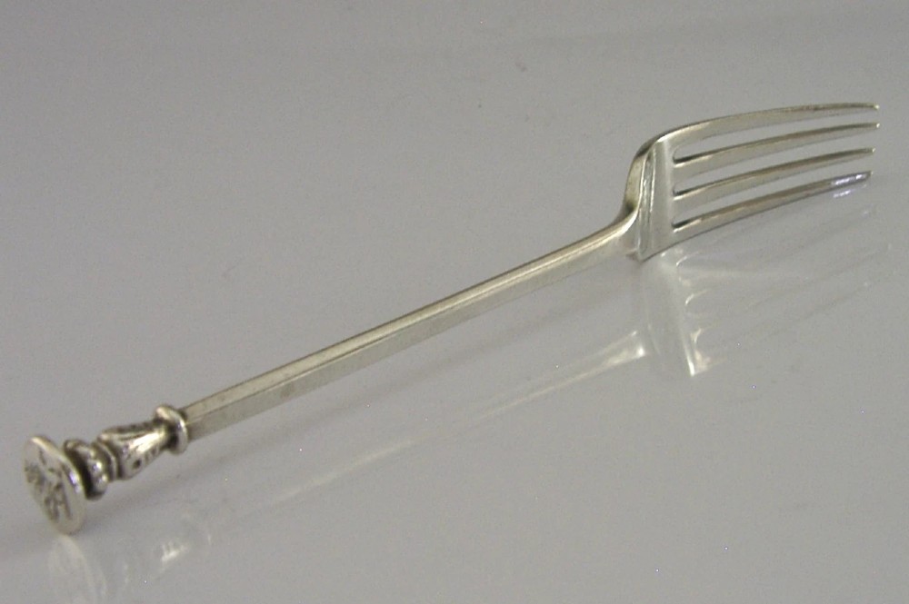 A Victorian sterling silver seal top fork featuring four tines and hallmarks along the slender stem. View V