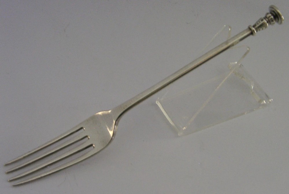 A Victorian sterling silver seal top fork featuring four tines and hallmarks along the slender stem. View VI