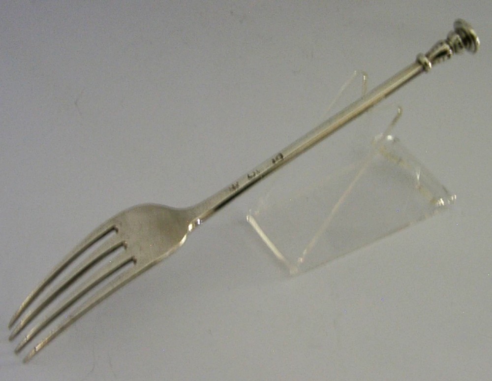 A Victorian sterling silver seal top fork featuring four tines and hallmarks along the slender stem. View VII