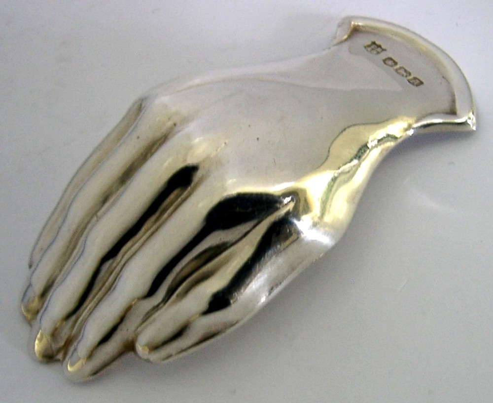 A sterling silver tea caddy spoon shaped like an open human hand with visible hallmarks stamped near the wrist handle. View II