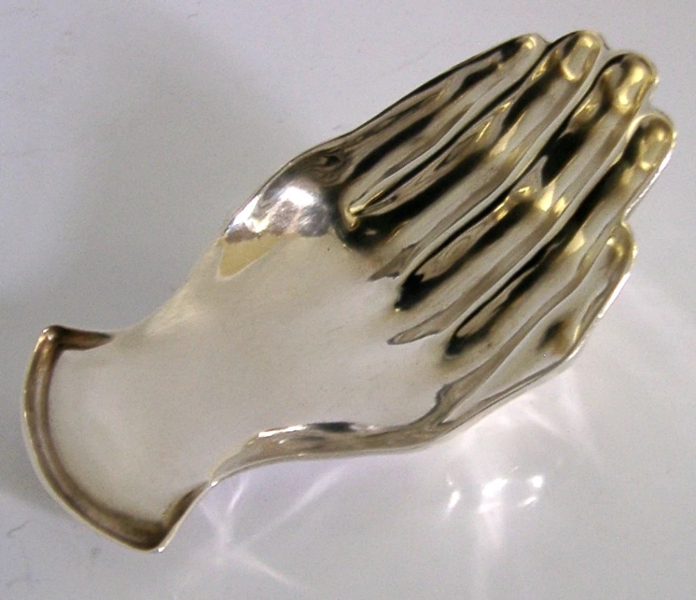 A sterling silver tea caddy spoon shaped like an open human hand with visible hallmarks stamped near the wrist handle. View III