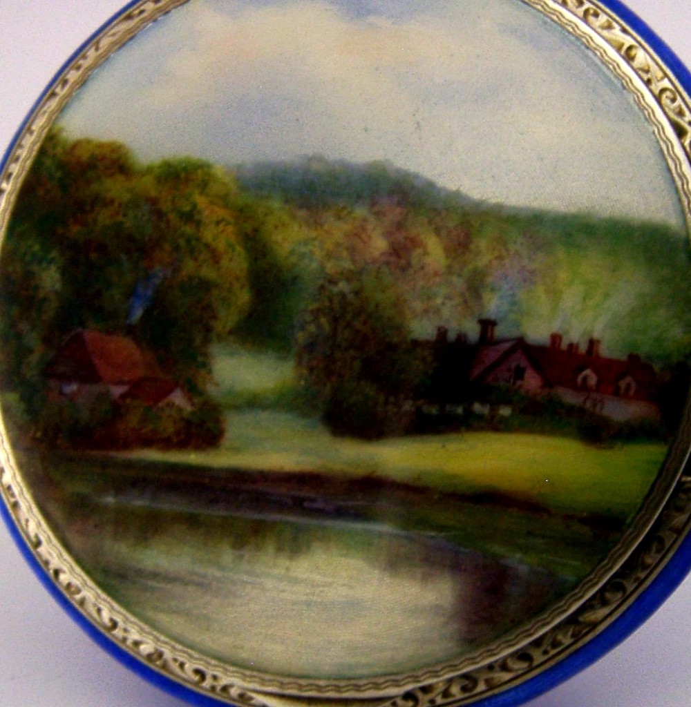 An open Art Deco sterling silver powder compact featuring a cobalt blue enamel rim and a hand-painted landscape scene on the lid interior. View II