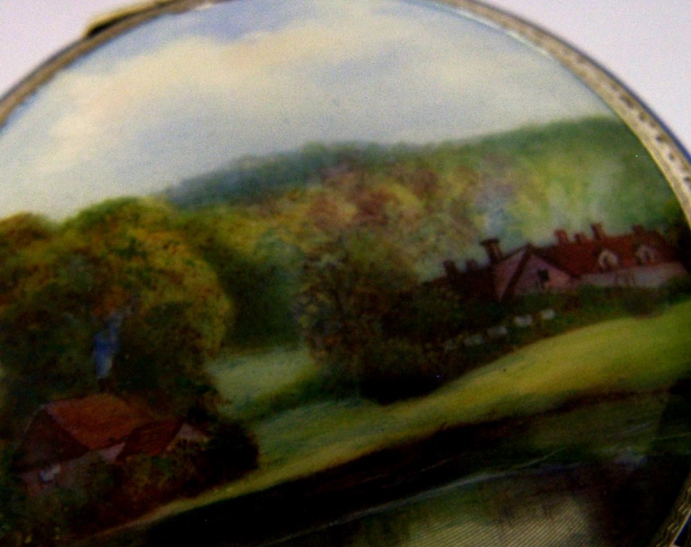 An open Art Deco sterling silver powder compact featuring a cobalt blue enamel rim and a hand-painted landscape scene on the lid interior. View IV