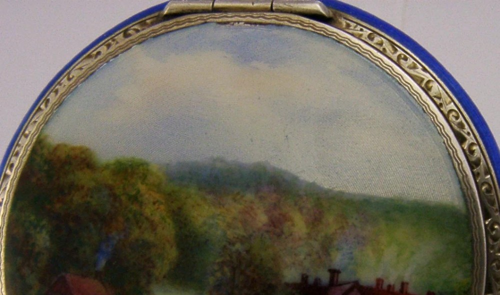 An open Art Deco sterling silver powder compact featuring a cobalt blue enamel rim and a hand-painted landscape scene on the lid interior. View XIII