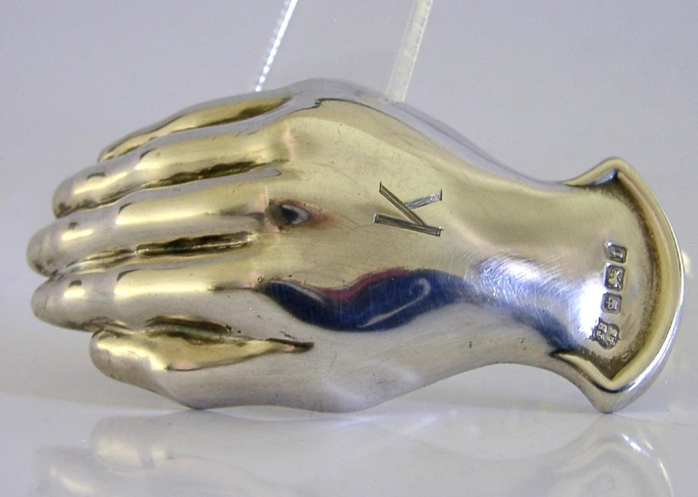 An Edwardian sterling silver tea caddy spoon crafted in the shape of a cupped human hand with an engraved monogram letter K and visible British hallmarks.