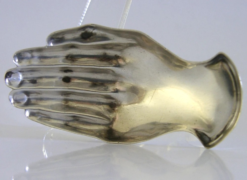 An Edwardian sterling silver tea caddy spoon crafted in the shape of a cupped human hand with an engraved monogram letter K and visible British hallmarks. View II