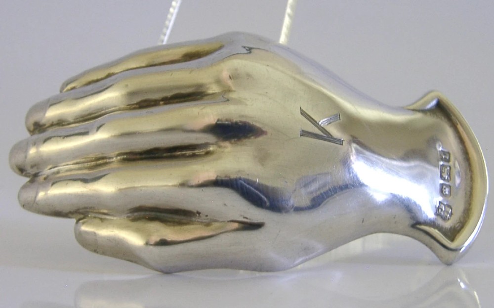 An Edwardian sterling silver tea caddy spoon crafted in the shape of a cupped human hand with an engraved monogram letter K and visible British hallmarks. View IV
