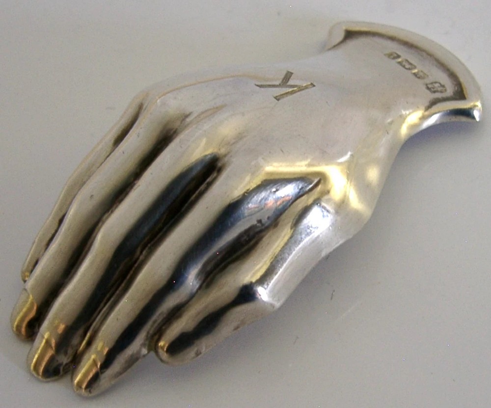 An Edwardian sterling silver tea caddy spoon crafted in the shape of a cupped human hand with an engraved monogram letter K and visible British hallmarks. View V