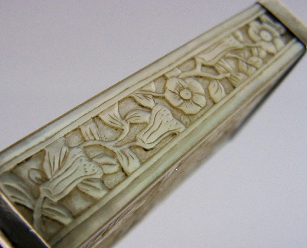 A small tapered antique Chinese export silver etui featuring intricately carved cream-coloured relief panels depicting figures in a garden setting. View VI