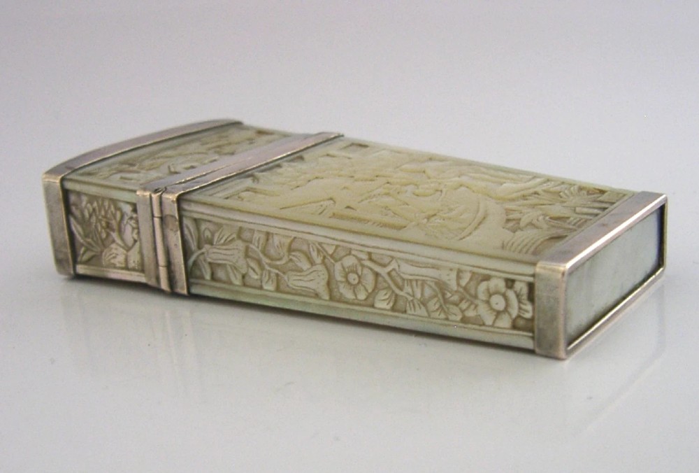 A small tapered antique Chinese export silver etui featuring intricately carved cream-coloured relief panels depicting figures in a garden setting. View VII