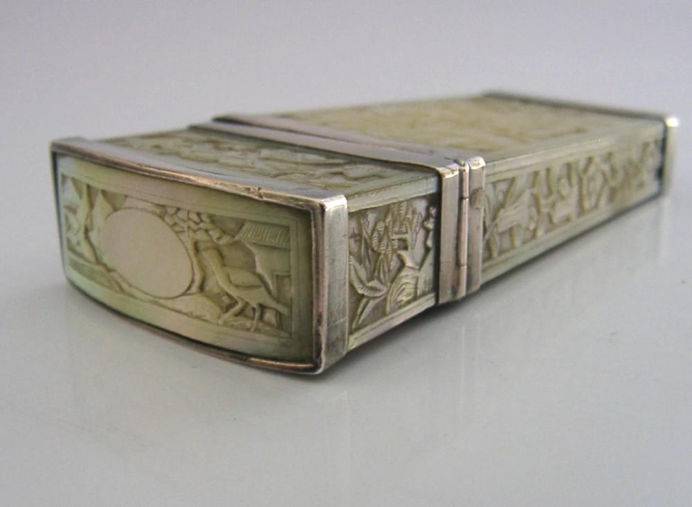 A small tapered antique Chinese export silver etui featuring intricately carved cream-coloured relief panels depicting figures in a garden setting. View IX
