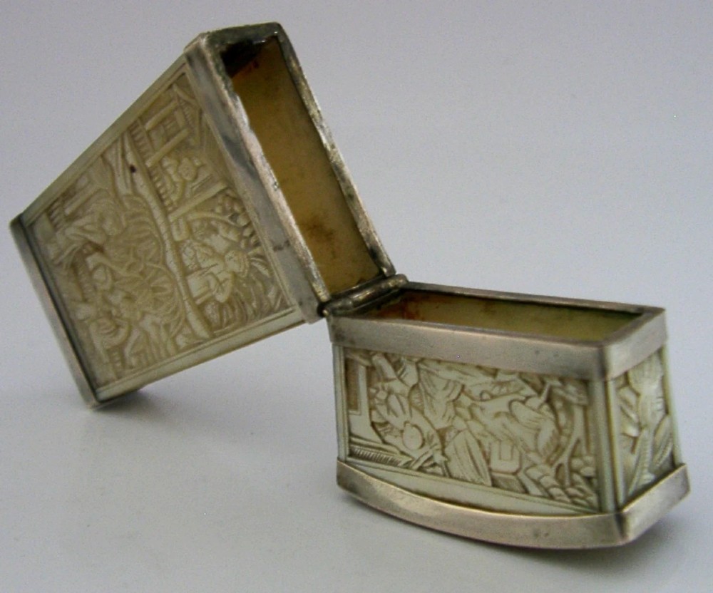 A small tapered antique Chinese export silver etui featuring intricately carved cream-coloured relief panels depicting figures in a garden setting. View X