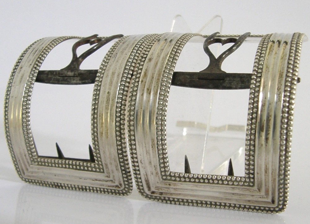 A pair of curved Georgian sterling silver shoe buckles featuring beaded borders and steel mechanism prongs.