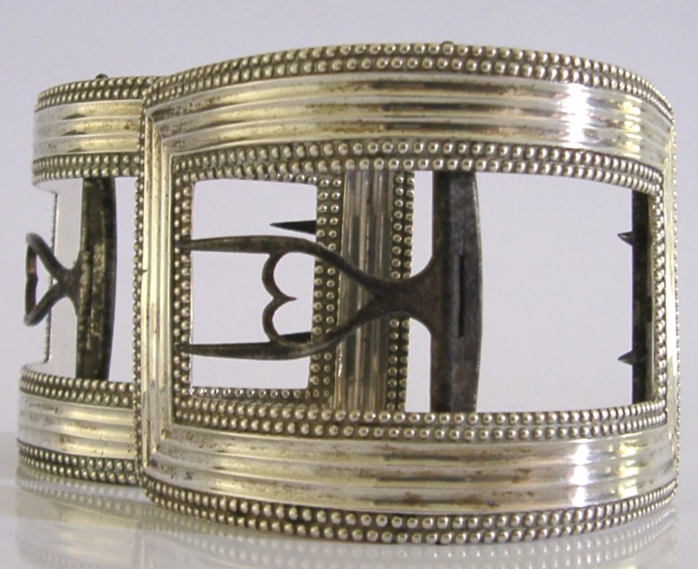 A pair of curved Georgian sterling silver shoe buckles featuring beaded borders and steel mechanism prongs. View II