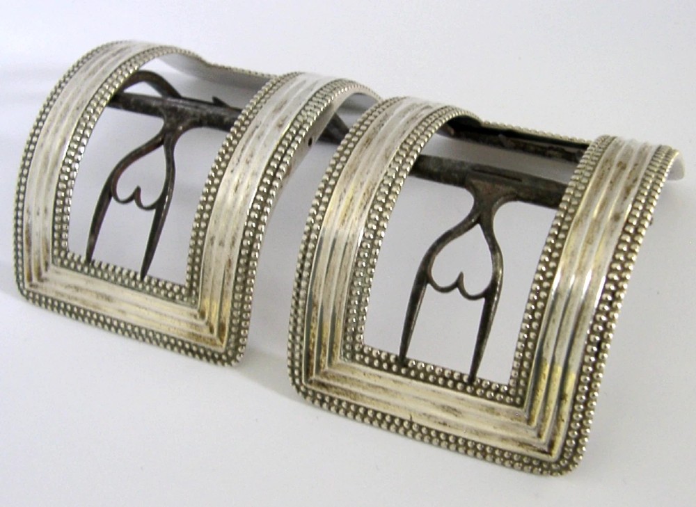 A pair of curved Georgian sterling silver shoe buckles featuring beaded borders and steel mechanism prongs. View IV