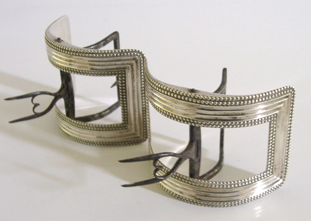 A pair of curved Georgian sterling silver shoe buckles featuring beaded borders and steel mechanism prongs. View V