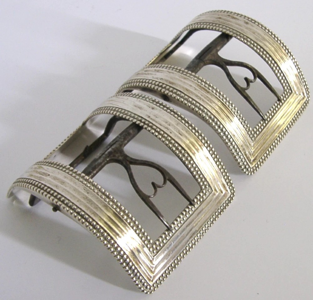 A pair of curved Georgian sterling silver shoe buckles featuring beaded borders and steel mechanism prongs. View VI
