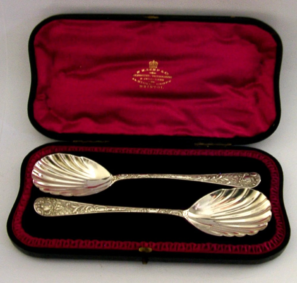 A pair of Victorian sterling silver serving spoons with scalloped shell bowls in a fitted red satin and black velvet presentation case.