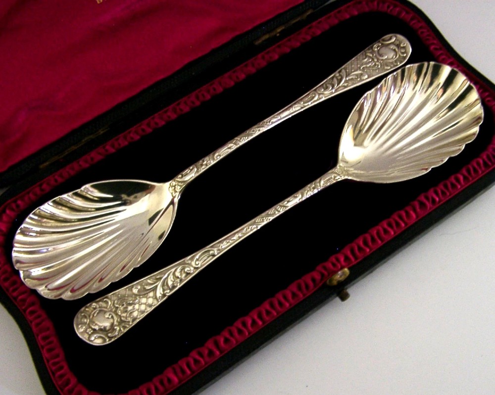 A pair of Victorian sterling silver serving spoons with scalloped shell bowls in a fitted red satin and black velvet presentation case. View II