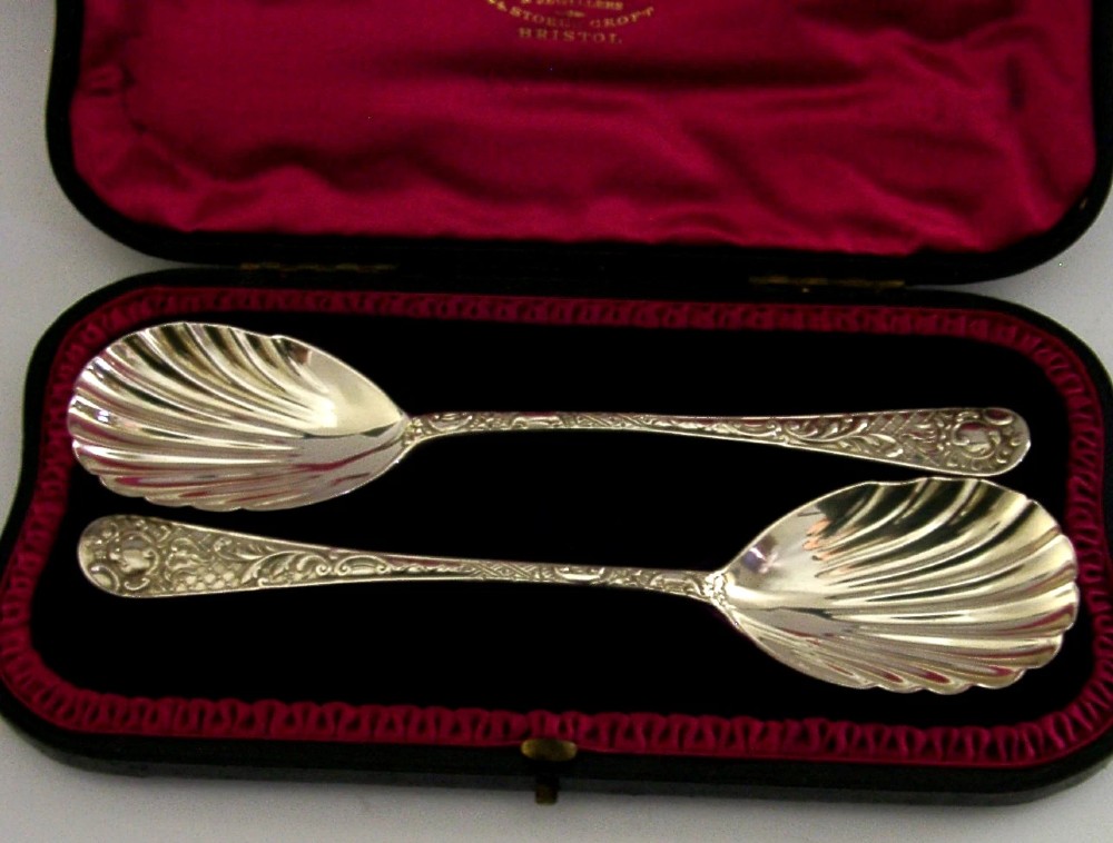A pair of Victorian sterling silver serving spoons with scalloped shell bowls in a fitted red satin and black velvet presentation case. View IV