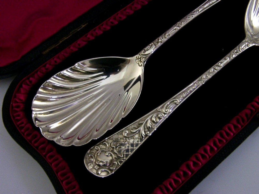 A pair of Victorian sterling silver serving spoons with scalloped shell bowls in a fitted red satin and black velvet presentation case. View V