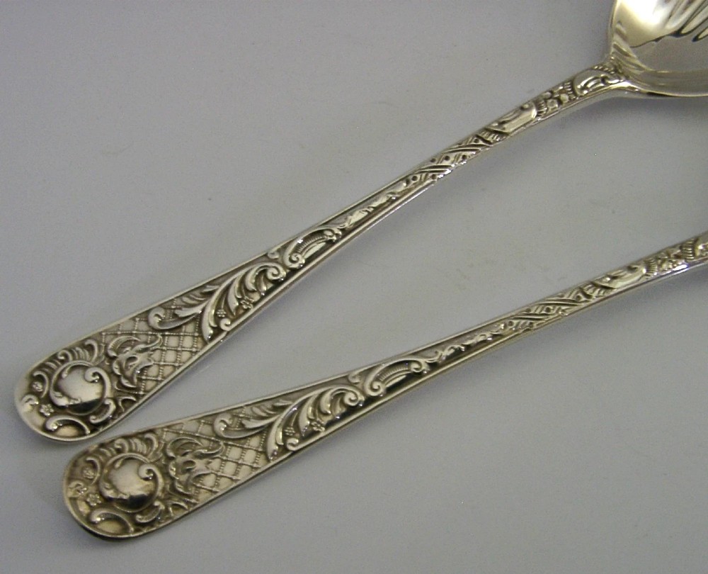 A pair of Victorian sterling silver serving spoons with scalloped shell bowls in a fitted red satin and black velvet presentation case. View VI