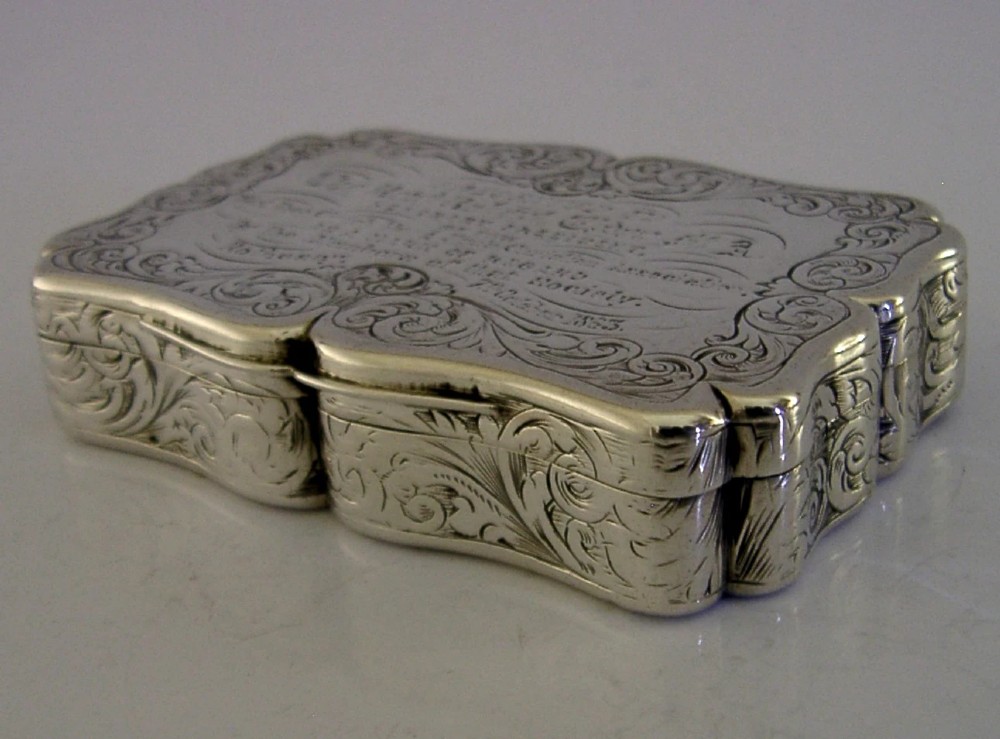 An engraved Victorian sterling silver snuff box with shaped edges, scrollwork border, and engraved inscription on the lid. View V