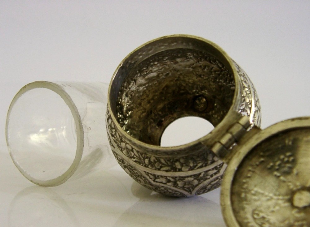 An antique hand-engraved solid silver mustard pot featuring arabesque foliage patterns, a hinged lid with finial, a spoon aperture, and three ball feet. View VIII