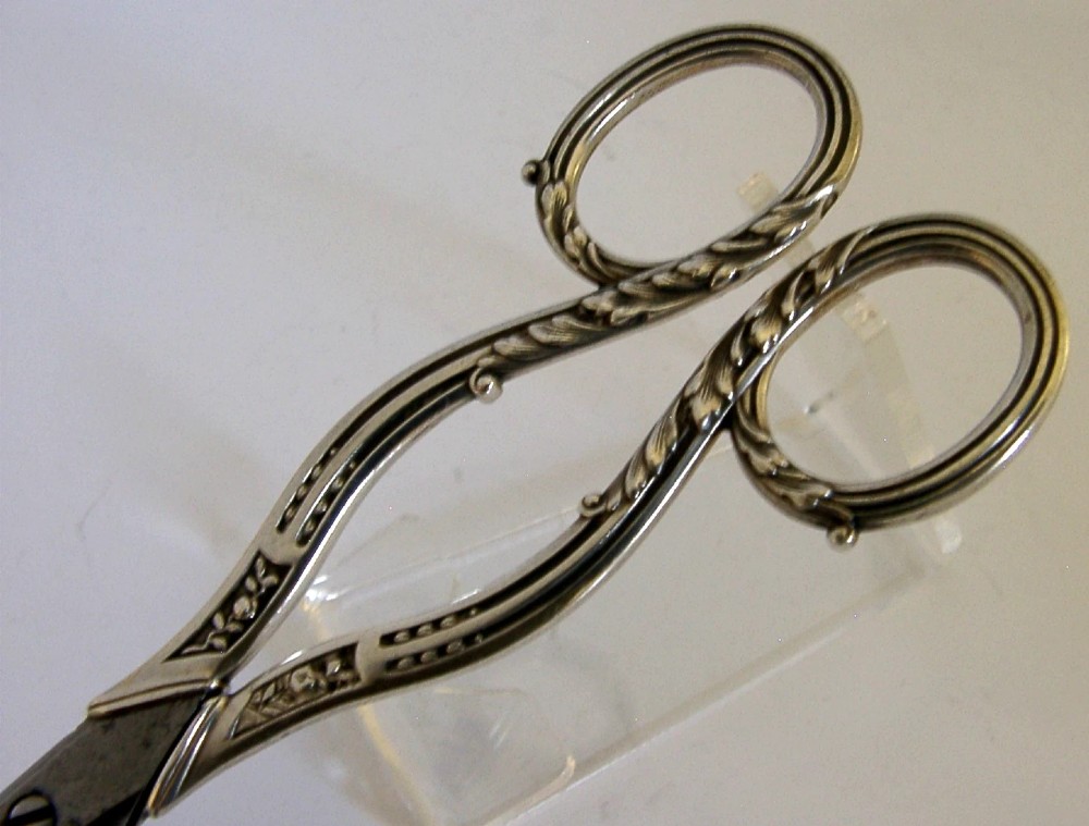 Antique French scissors featuring ornate sterling silver handles decorated with relief foliage motifs and tapered steel blades. View III