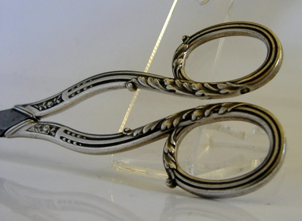 Antique French scissors featuring ornate sterling silver handles decorated with relief foliage motifs and tapered steel blades. View IV
