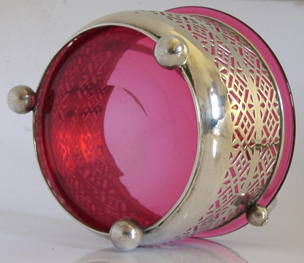 An Edwardian sterling silver pierced basket featuring a lattice geometric pattern, a swing handle, and a fitted cranberry red glass liner. View VIII