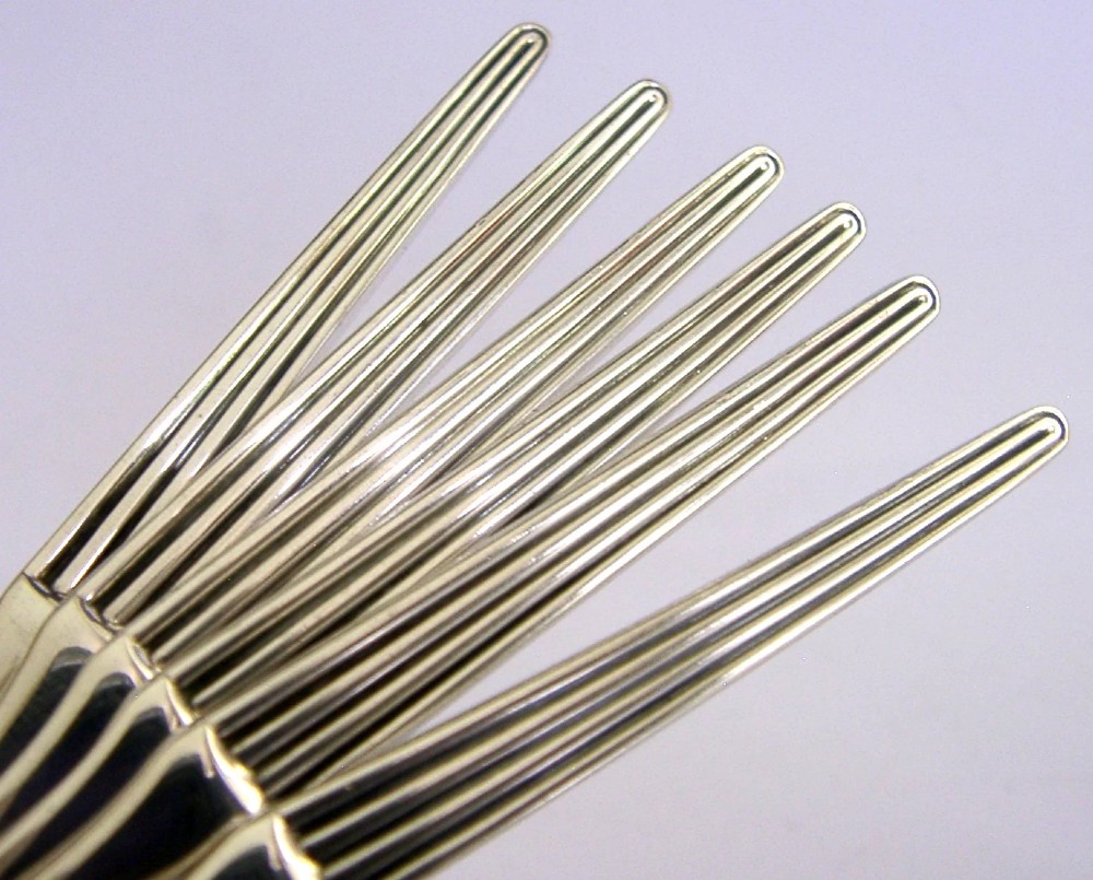 A set of six mid-century solid silver spoons featuring slim handles with reeded linear decoration and oval bowls. View II