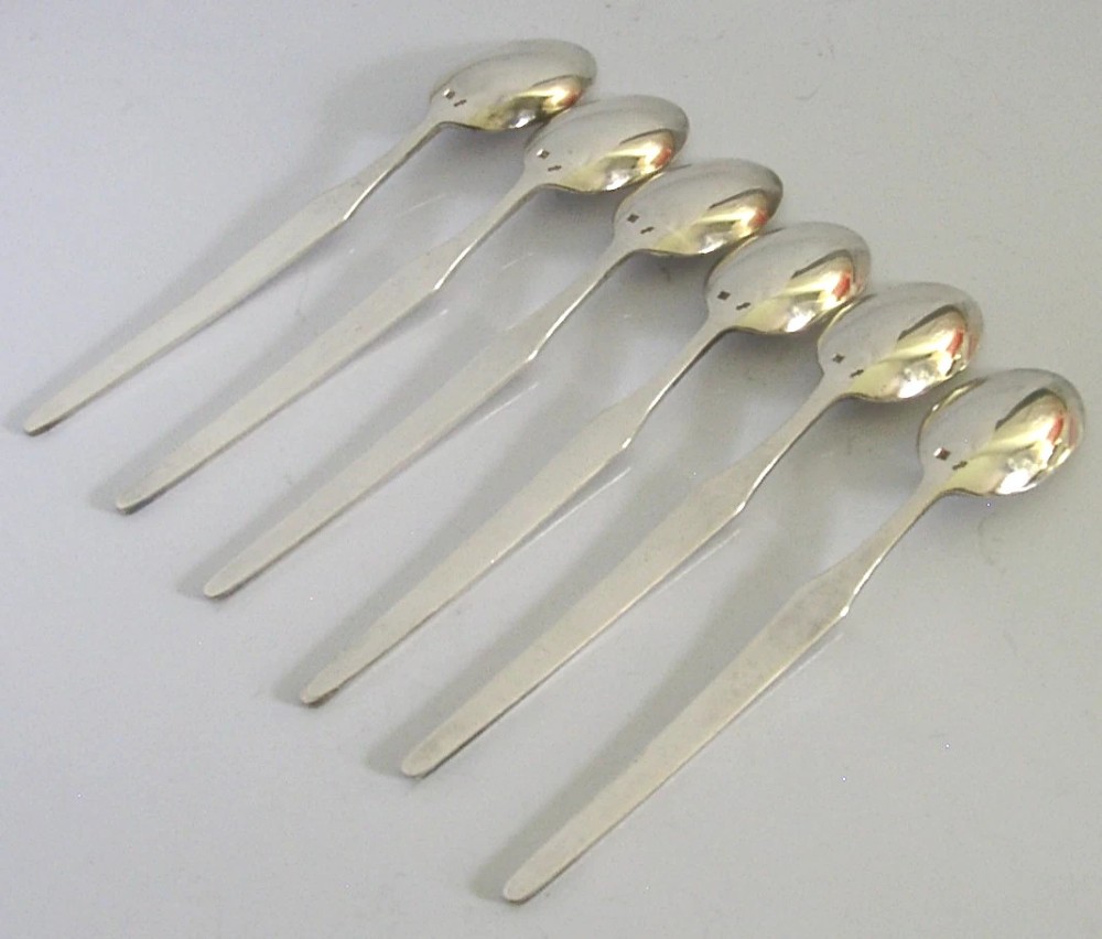 A set of six mid-century solid silver spoons featuring slim handles with reeded linear decoration and oval bowls. View V