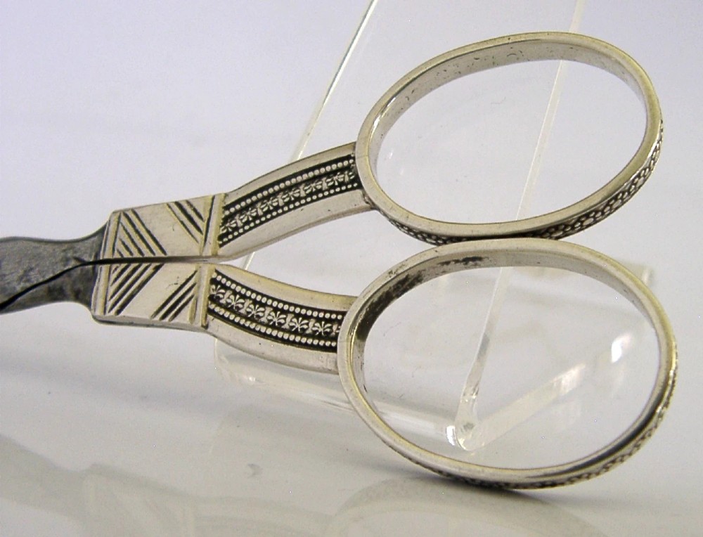 A pair of 19th-century Dutch solid silver needlework scissors featuring engraved oval finger loops and steel blades. View II