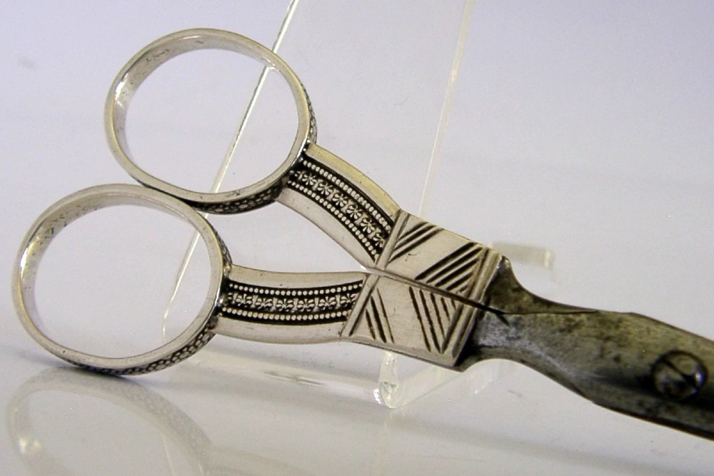 A pair of 19th-century Dutch solid silver needlework scissors featuring engraved oval finger loops and steel blades. View V
