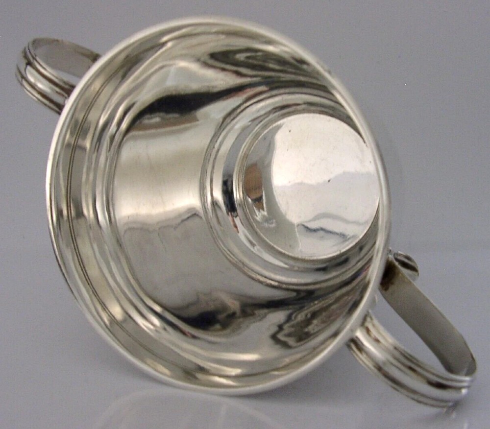 A polished sterling silver porringer bowl featuring a flared rim, rounded body, and twin loop side handles. View IV