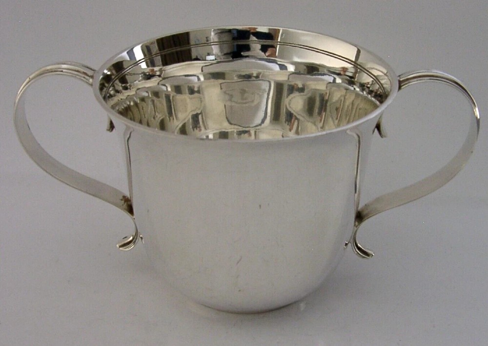 A polished sterling silver porringer bowl featuring a flared rim, rounded body, and twin loop side handles. View V