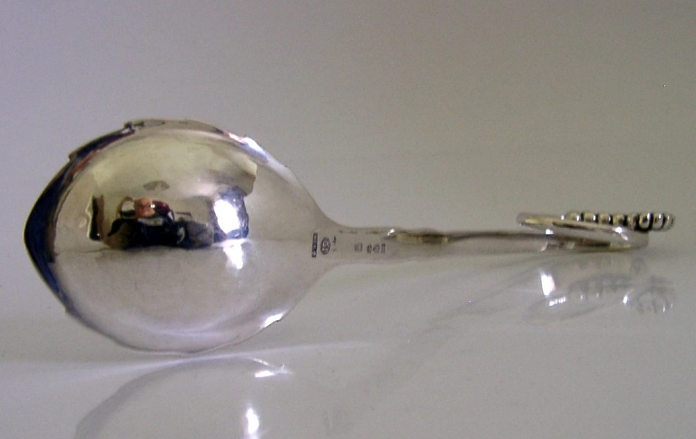 A sterling silver Georg Jensen spoon featuring a curved loop handle detailed with beaded ornamentation and a shallow oval bowl. View V
