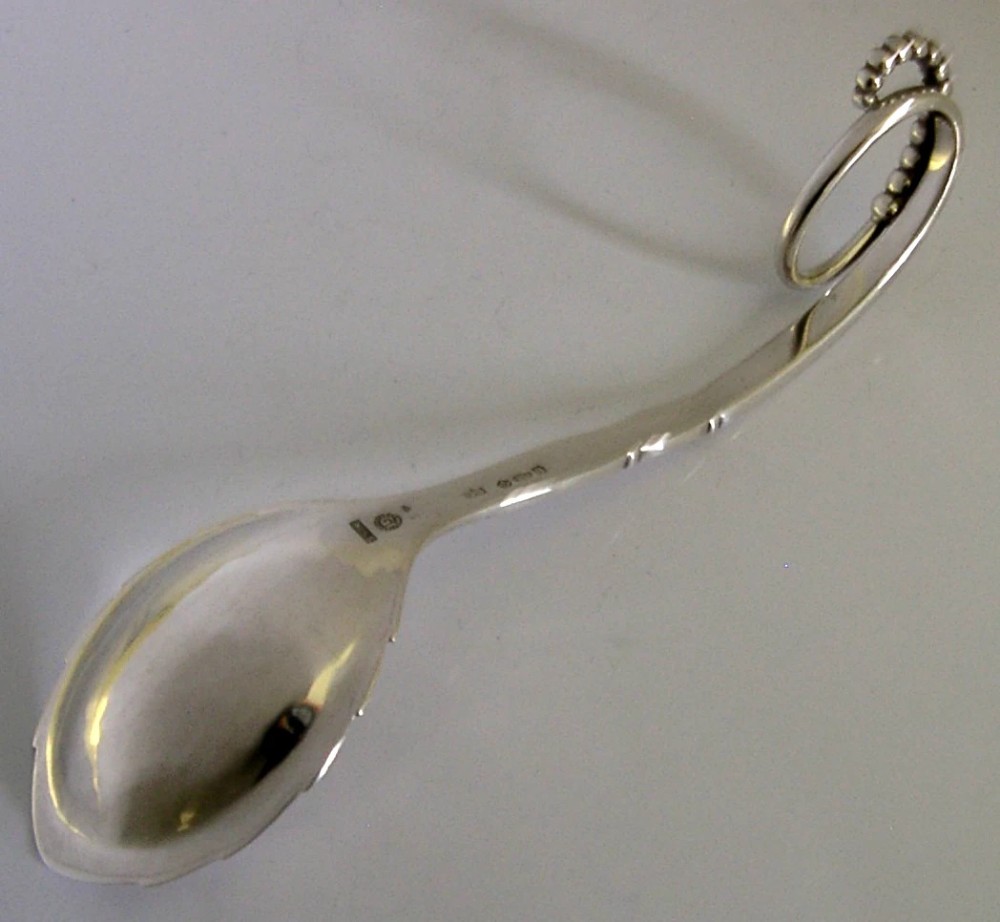 A sterling silver Georg Jensen spoon featuring a curved loop handle detailed with beaded ornamentation and a shallow oval bowl. View VI