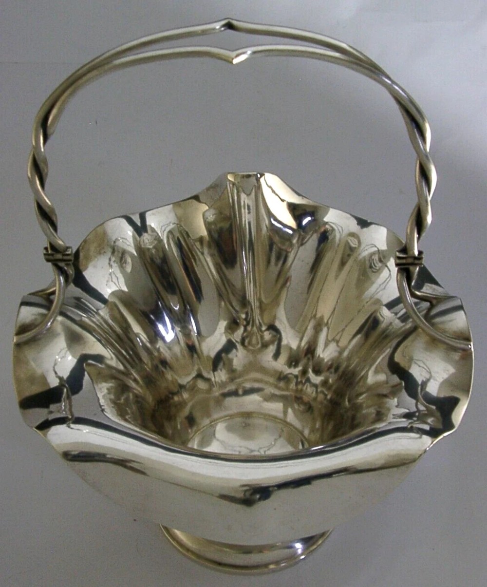 An antique solid silver Art Nouveau basket bowl with a fluted, lobed rim and an overhead twisted wire swing handle. View V