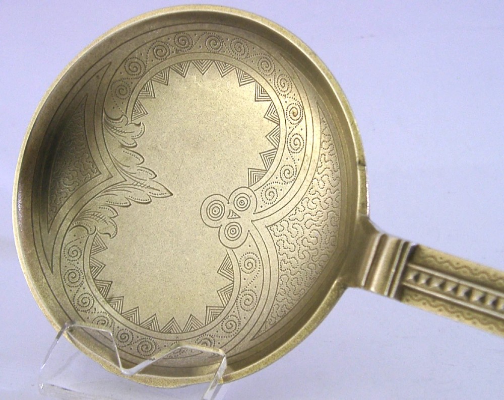 An antique Danish solid silver gilt serving spoon featuring an engraved circular bowl, a twisted stem, and a decorative finial. View V