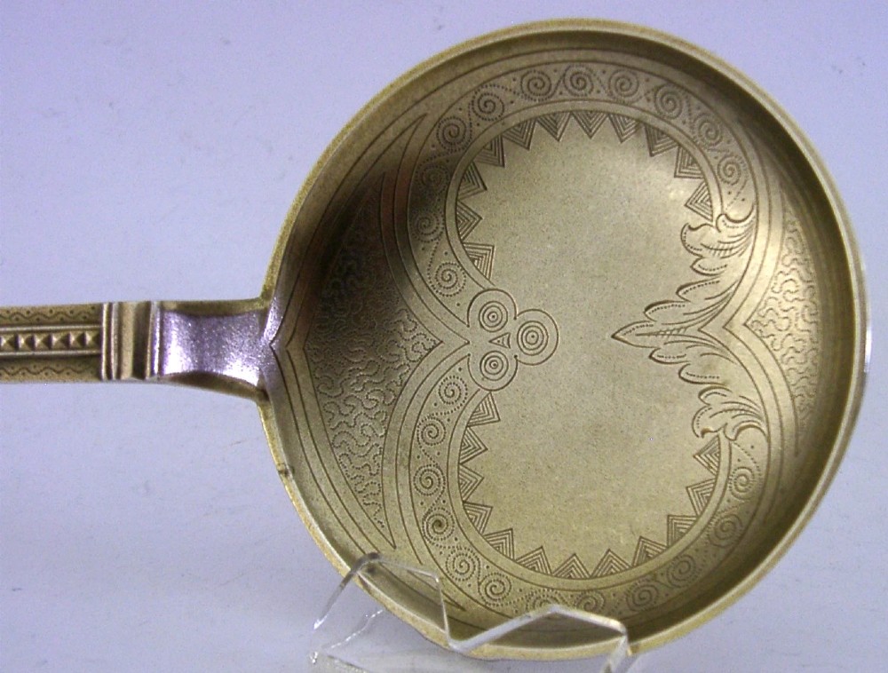An antique Danish solid silver gilt serving spoon featuring an engraved circular bowl, a twisted stem, and a decorative finial. View VII