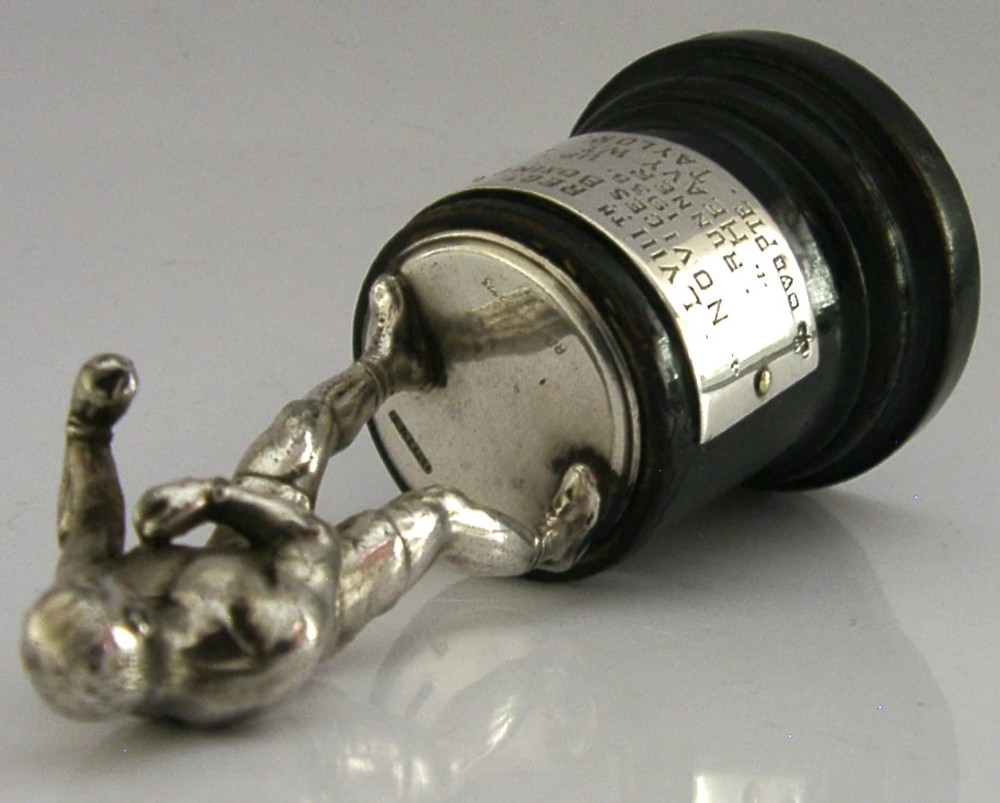 A silver-plated figurine of a boxer in a fighting stance mounted on a dark cylindrical wooden base with an engraved inscription plate. View IV