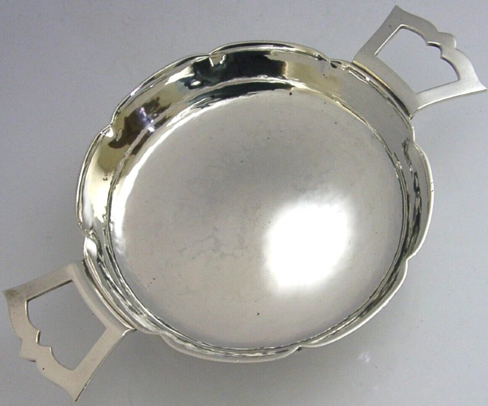 A planished sterling silver quaich featuring a lobed shallow bowl and two flat geometric handles.