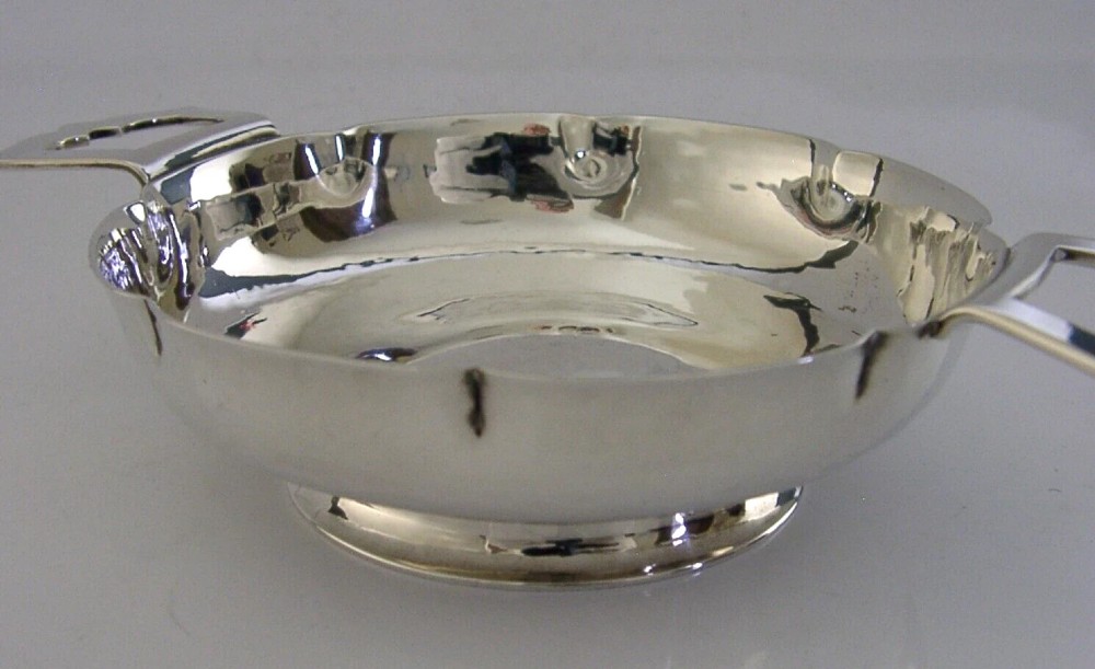 A planished sterling silver quaich featuring a lobed shallow bowl and two flat geometric handles. View IV