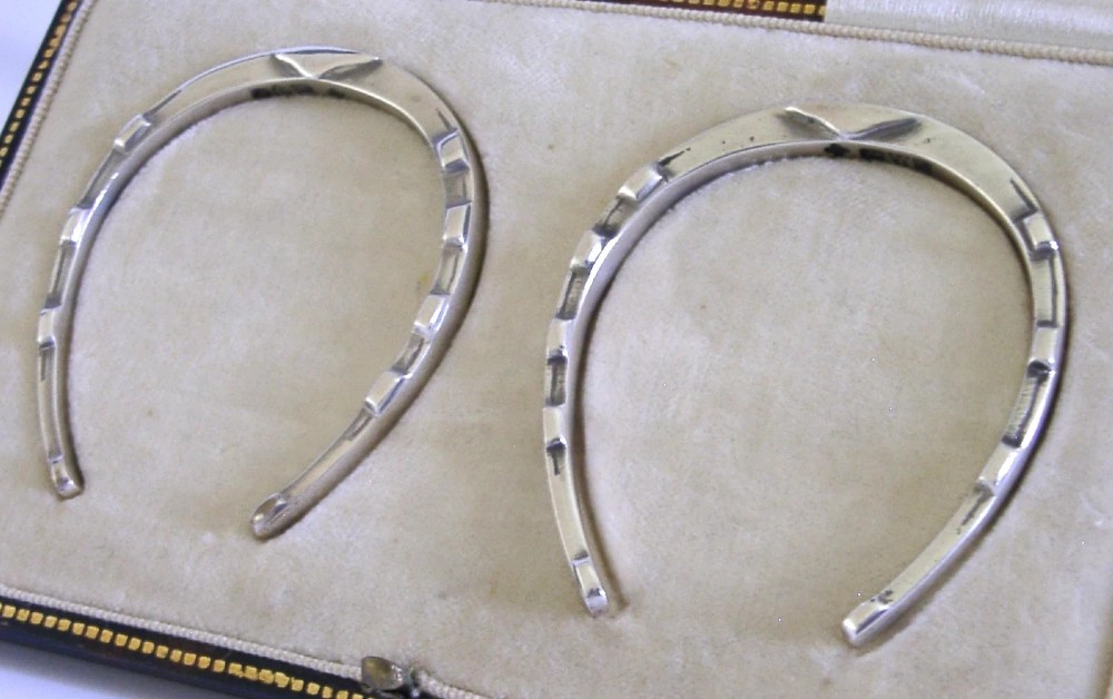 A pair of sterling silver horseshoe-shaped napkin rings presented inside a silk-lined leatherette presentation box. View II