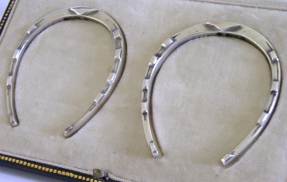 A pair of sterling silver horseshoe-shaped napkin rings presented inside a silk-lined leatherette presentation box. View IV