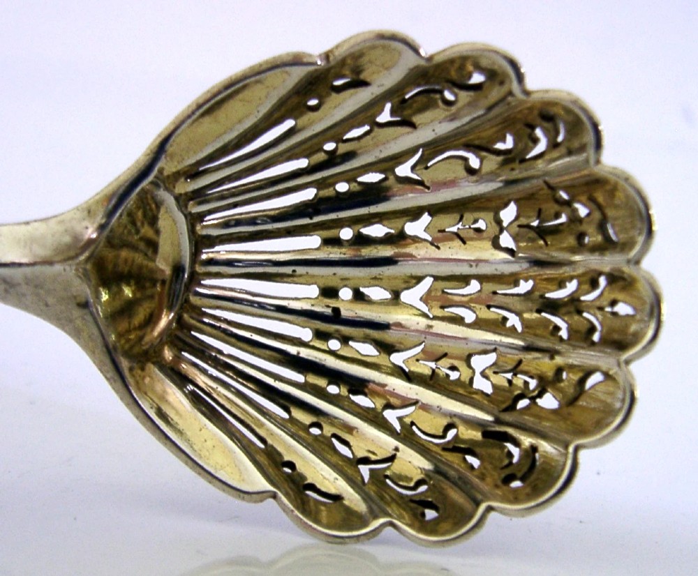 Victorian sterling silver sugar sifter spoon featuring a twisted stem, shell-shaped pierced bowl, and engraved heron crest handle terminal. View II