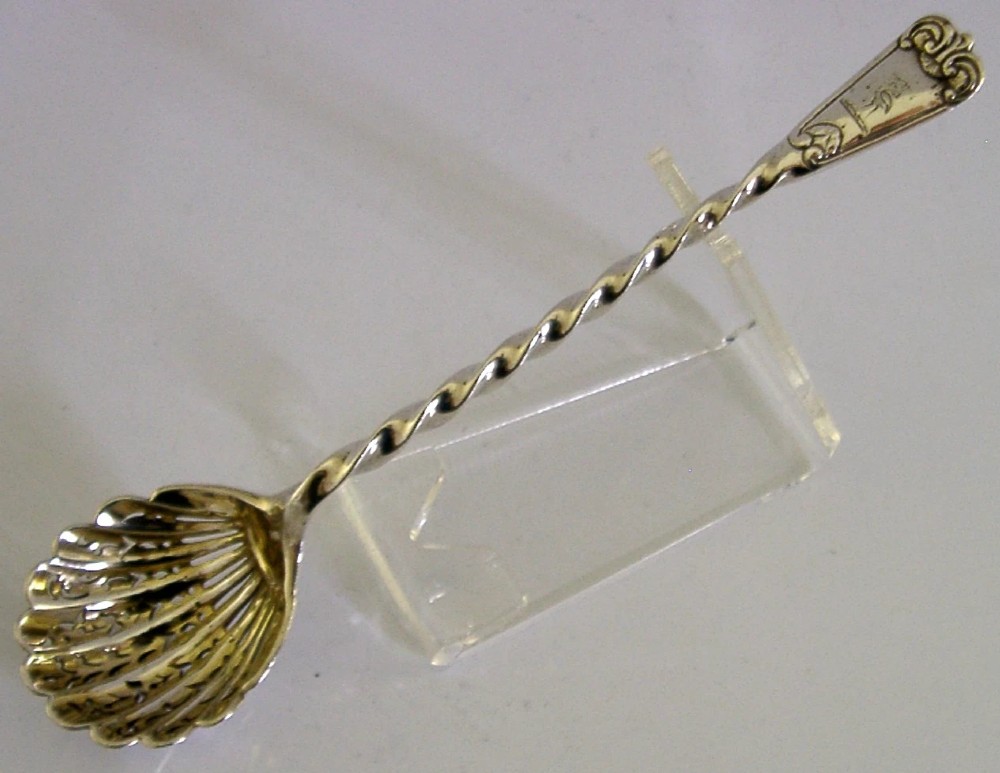 Victorian sterling silver sugar sifter spoon featuring a twisted stem, shell-shaped pierced bowl, and engraved heron crest handle terminal. View IV